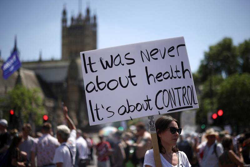 A woman holds a placard during an anti-lockdown and anti-vaccine protest near the Houses of Parliament, London, on June 14, 2021. Reuters