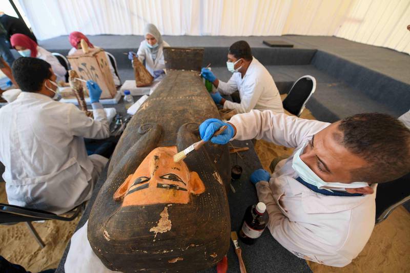 An archaeologist cleans a sarcophagus during the unveiling of an ancient treasure trove of more than a 100 intact sarcophagi. AFP