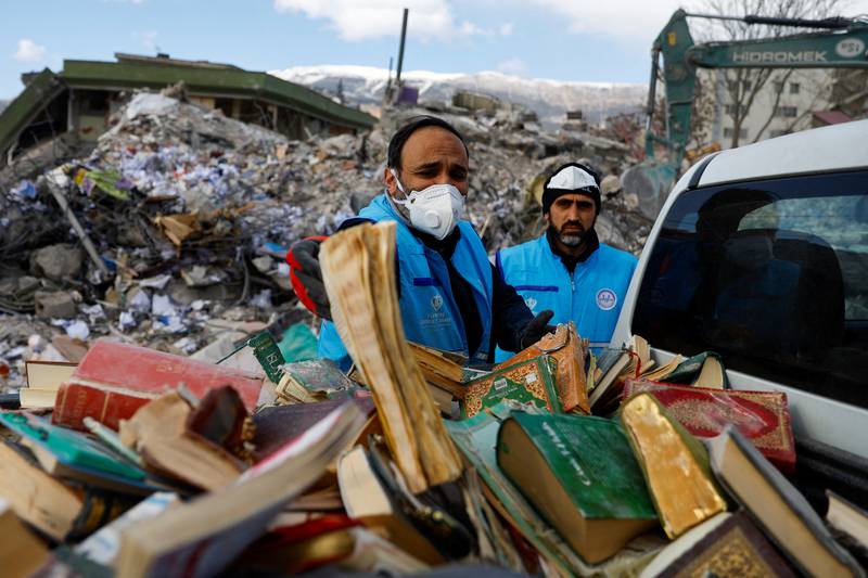 People collect copies of holy books from the rubble in Kahramanmaras. Reuters