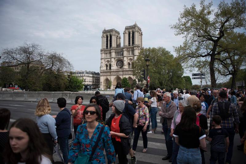 epa07521530 Tourists walks front of Notre Dame de Paris after a new smaller security area was applied by the French police in Paris, France, 22 April 2019. A fire started in the late afternoon 15 April in one of the most visited monuments of the French capital.  EPA/Julien de Rosa