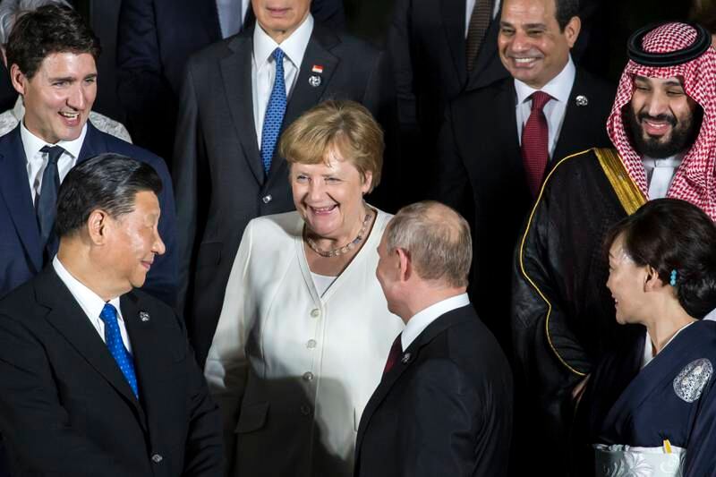 Mrs Merkel speaks to China's President Xi Jinping and Russia's President Vladimir Putin during a group photo session in front of Japan's Osaka Castle, at the G20 summit in June 2019. Getty Images