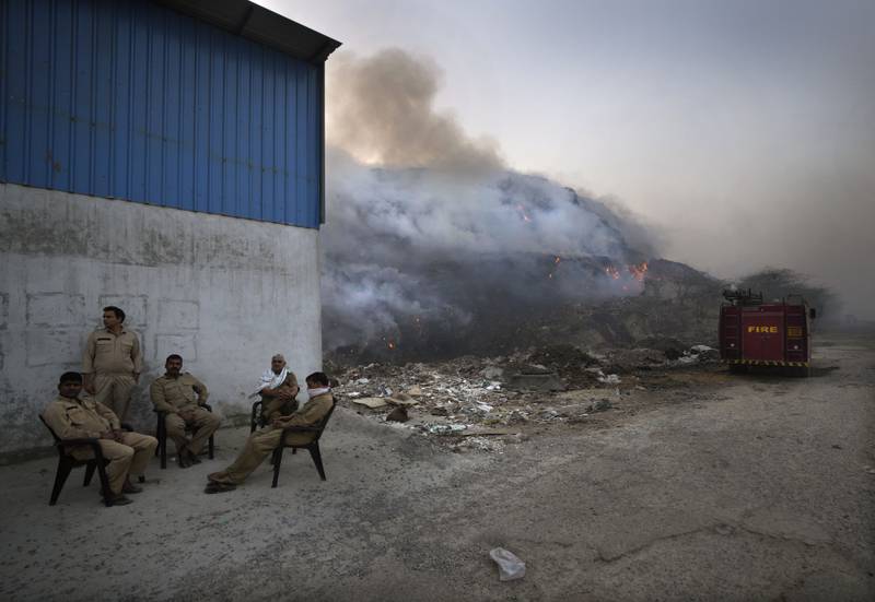 Delhi fire officials take a break while fighting a fire at the Bhalswa landfill in New Delhi.  Every day more than 2,300 tonnes of waste are dumped at the landfill without being segregated, resulting in the build-up of combustible methane gas. AP Photo