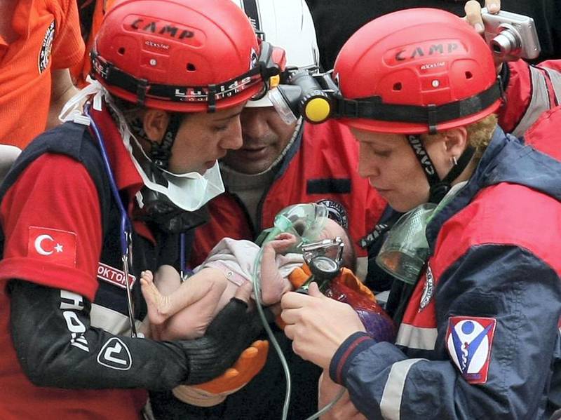 Rescuers carry two-week-old baby girl Azra Karaduman from the rubble of a collapsed building in Ercis, Turkey's eastern province of Van, on October 25, 2011. Crowds cheered and applauded as 73-year-old Gulzade Karaduman was carried into an ambulance, hours after her tiny granddaughter Azra and then her daughter Seniha Karaduman were pulled free from the wreckage of the family home in the eastern town of Ercis. As the death toll reached 459 and the Red Crescent warned that hundreds or even thousands of people remained buried under the debris from Sunday's quake, the triple rescue provided vital relief amid the otherwise grim task.      AFP PHOTO / ADEM ALTAN (Photo by ADEM ALTAN / AFP)
