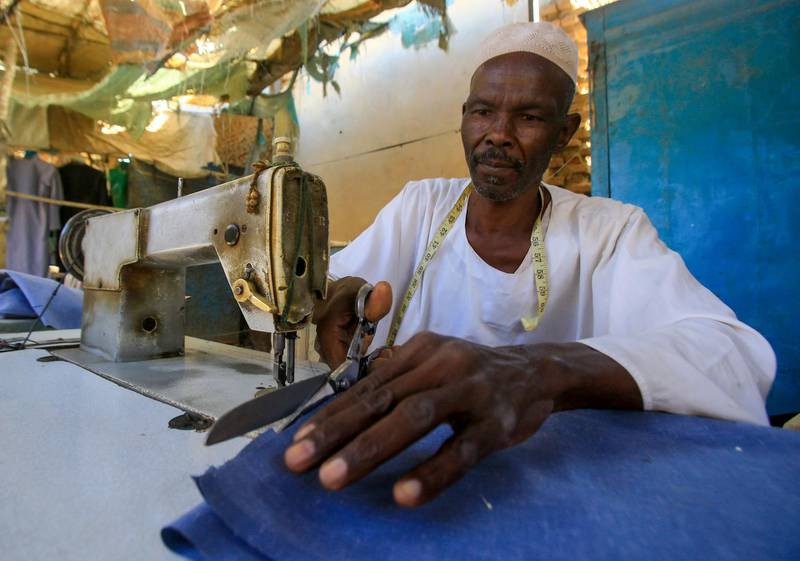A displaced Sudanese tailor cuts textiles at his workshop at the Abu Shouk camp for internally displaced persons, 20 km north of El-Fasher, the capital of the North Darfur state. AFP