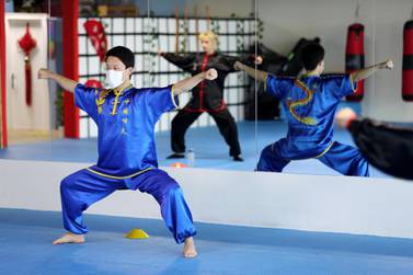 Coach Jaimi Woang holds a semi squat position during a tai chi session. Chris Whiteoak / The National