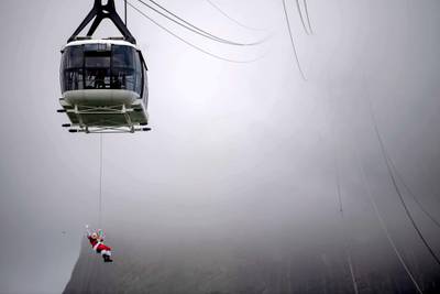 A man disguised as Santa Claus, suspended from the Sugar Loaf's Cable car, waves at visitors upon arrival to the Sugar Loaf mountain, in Rio de Janeiro, Brazil.   AFP