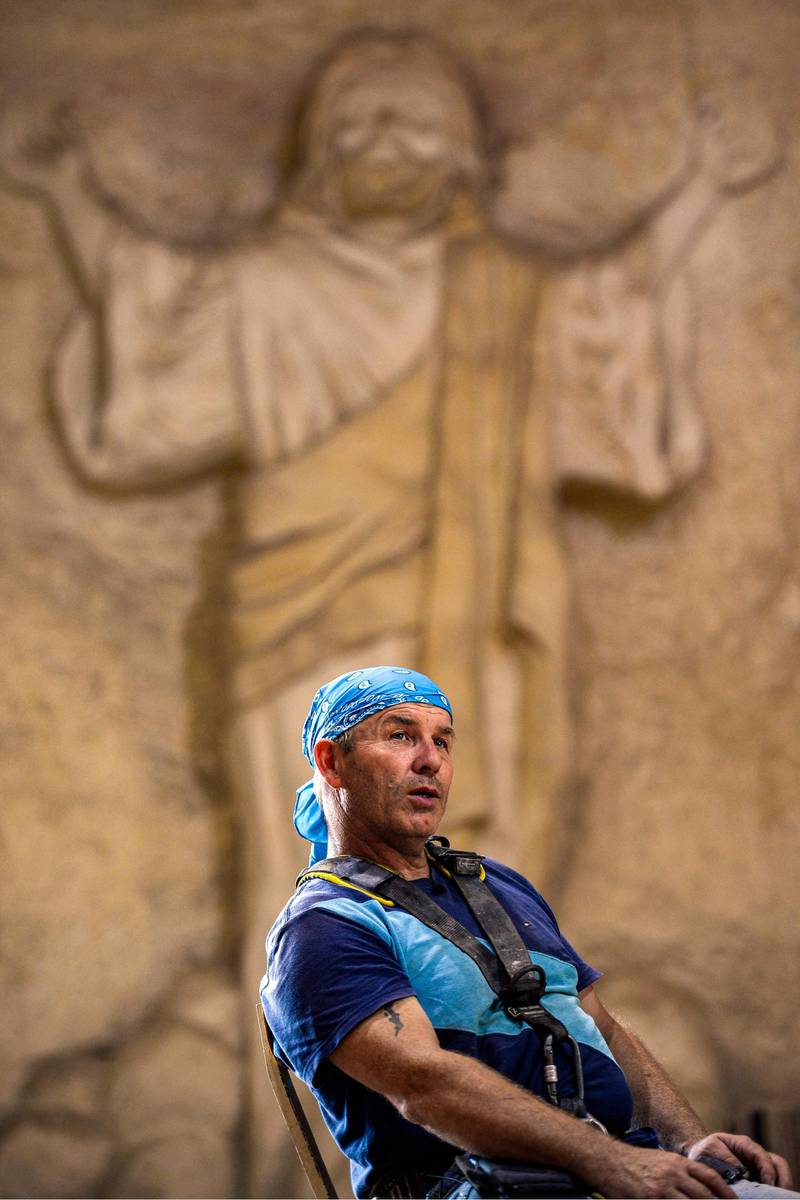 Polish artist Mario, sculptor of St. Simon the Tanner Monastery complex, speaks before a relief depicting Christ with outstretched hands, during an interview with AFP at the church in the Egyptian capital Cairo's eastern hillside Mokattam district. Mario spent more than two decades carving the rugged insides of the seven cave churches and chapels of the rock-hewn St. Simon Monastery and church complex atop Cairo's Mokattam hills, with designs inspired by biblical stories. It was all done to fulfil the wishes of the church's parish priest who met Mario in the early 1990s in Cairo. The Polish artist, who had arrived in Egypt earlier on an educational mission, was then looking for an opportunity to serve God at the monastery. AFP