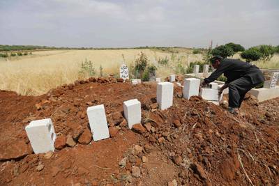 A Syrian man puts white stones over the tombs of five victims of a regime air strike on the village of Kafr Aweid in which five people, including two children, were killed  following their burial together in the country's northern Idlib province. AFP