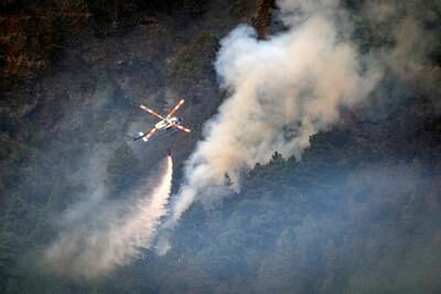 A helicopter drops water on to flames advancing towards the town of Pinolere. AP