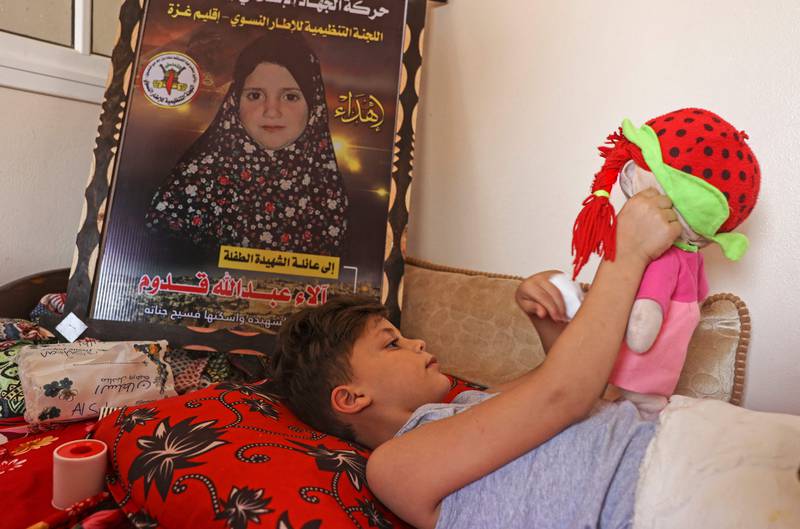 Wounded Palestinian Rayed Qadoom lies near a poster depicting his five-year-old sister Alaa, who was killed during the latest conflict between Israel and Palestinian militants in Gaza. AFP