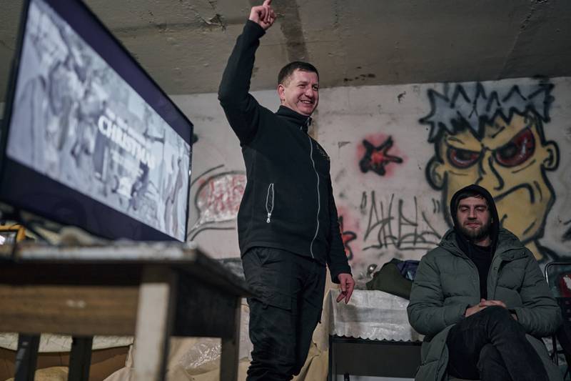 Chaplain Leonid, a policeman, preaches as he shows a religious Christmas film with a generator and TV set in an apartment house basement used as a bomb shelter in Avdiivka, Donetsk region. AP Photo