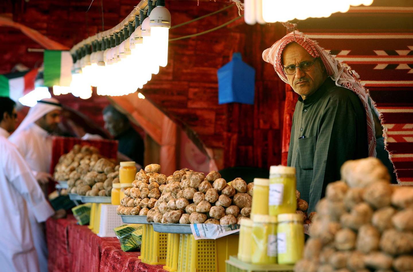 A Kuwaiti vendor stands behind his truffles for sale at a market in al-Rai, an industrial zone northwest of Kuwait City on March 1, 2018. 
White or beige, but never black, the "desert truffle" is a rare delicacy with a dedicated marketplace in Kuwait, where remnants of the Iraqi invasion and changing weather patterns have decimated local production. / AFP PHOTO / YASSER AL-ZAYYAT