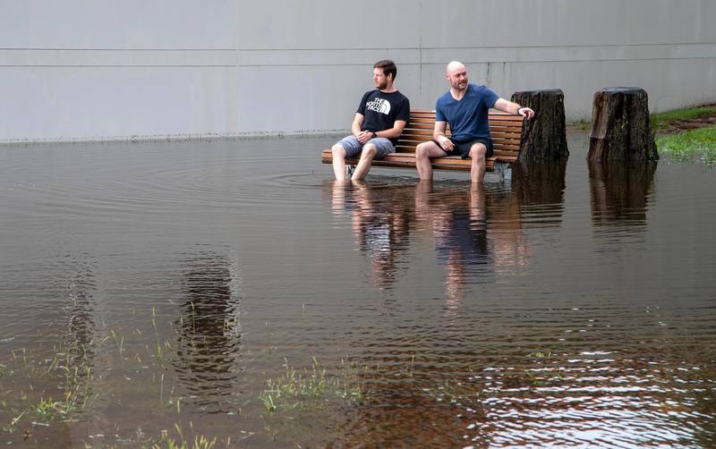 Two men sit on a bench in a flooded park in Port Stephens. AP