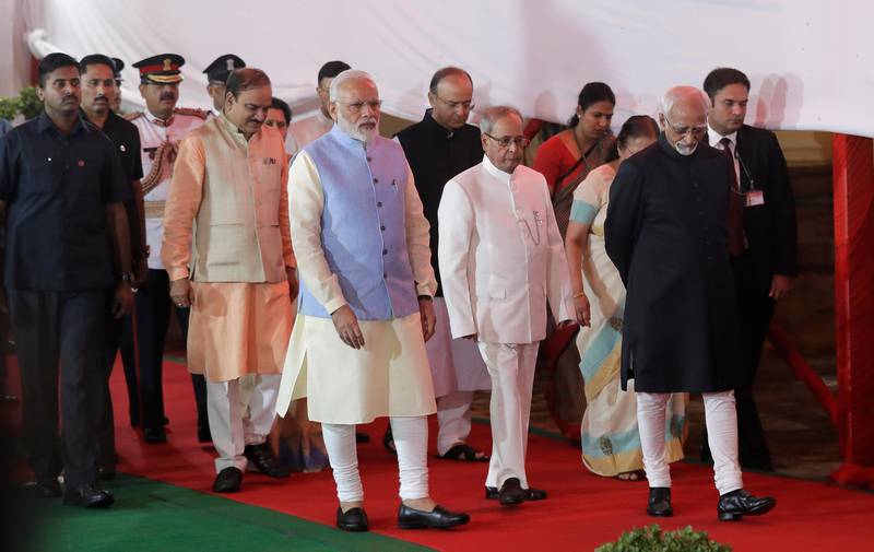 Indian Prime Minister Narendra Modi, center, Indian President Pranab Mukherjee, center right, and Indian Vice President Hamid Ansari, right, walk in a procession for a midnight session of parliament on Friday to launch the Goods and Services Tax (GST) in New Delhi, India. Manish Swarup / AP Photo