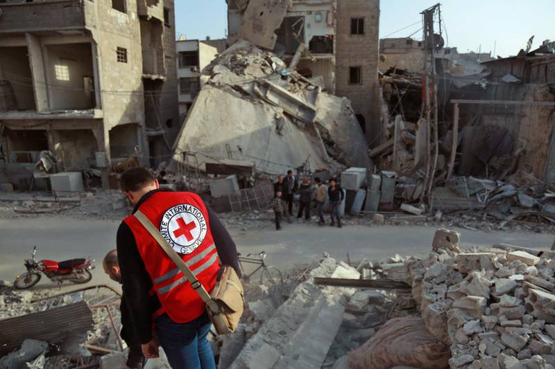 A International Red Cross volunteer stands above the rubble of a destroyed building in Douma in the Syrian rebel enclave of Eastern Ghouta on March 5, 2018 on the outskirts of Damascus. - An international convoy entered Syria's rebel enclave of Eastern Ghouta to deliver much-needed aid today as the regime pounded the region with fresh bombardment, killing dozens as it seized more ground. (Photo by HAMZA AL-AJWEH / AFP)