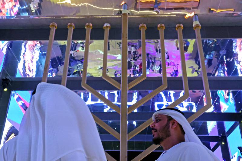 Emiratis stand in front of a large menorah. AFP
