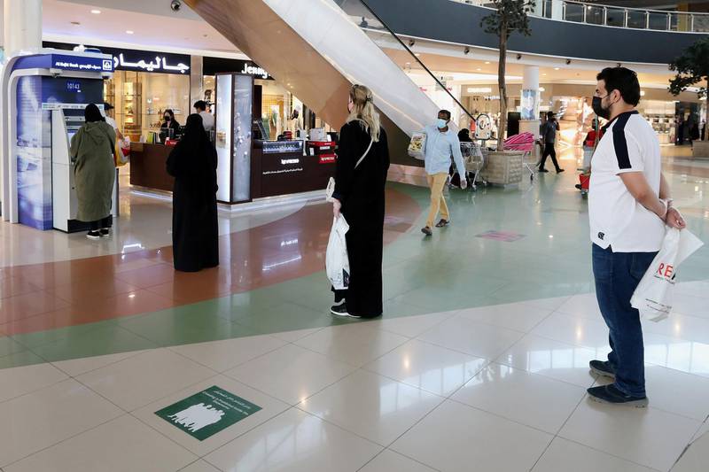 People line up while social distancing to use an ATM at a shopping mall in Saudi Arabia. Reuters