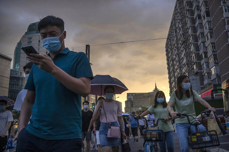 A man uses his smartphone as he walks across an intersection during the evening rush hour in Beijing. China’s smartphone sales fell 4 per cent yearly in the June quarter, reaching the lowest second-quarter sales figure since 2014. AP
