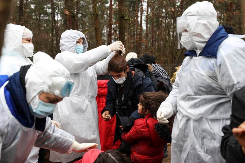 Belarusian doctors help people prepare to enter showering tents close to the logistics centre. EPA
