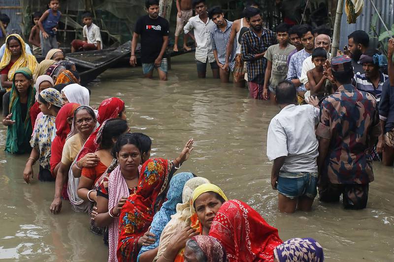 People queue in flood waters to collect food relief following heavy monsoon rainfalls in Sunamganj. At least 26 more people have died in flooding and lightning strikes in India as millions remained marooned in the country and neighbouring Bangladesh.  AFP