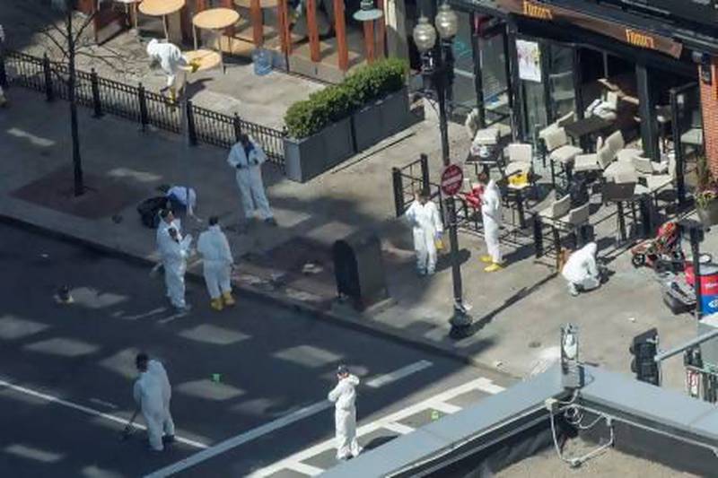 Evidence technicians work at the site of one of the bombings on Boylston Street as an investigation continues into the bombings near the finish line of the Boston Marathon.