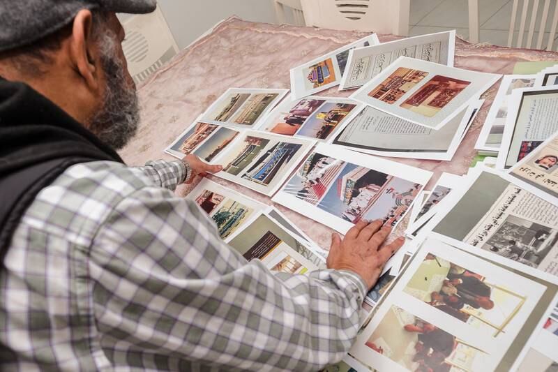 He sorts through photos of some of the hundreds of street signs he has written over the years.