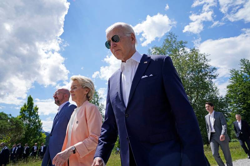 Mr Biden walks with Ms von der Leyen and Mr Michel. Reuters