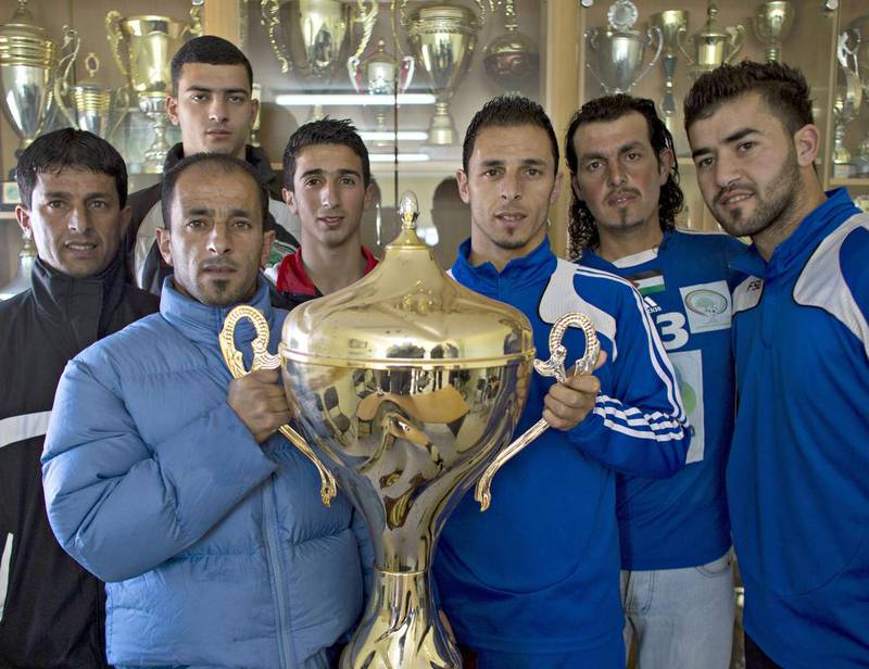 Abu Hammad’s family members pose with the Yasser Arafat Cup. Despite the lack of facilities, Wadi Al Nees has defeated bigger clubs that spent hundreds of thousands of dollars to buy players. The top league is professional and all players draw salaries, including those from Wadi Al Nees.
