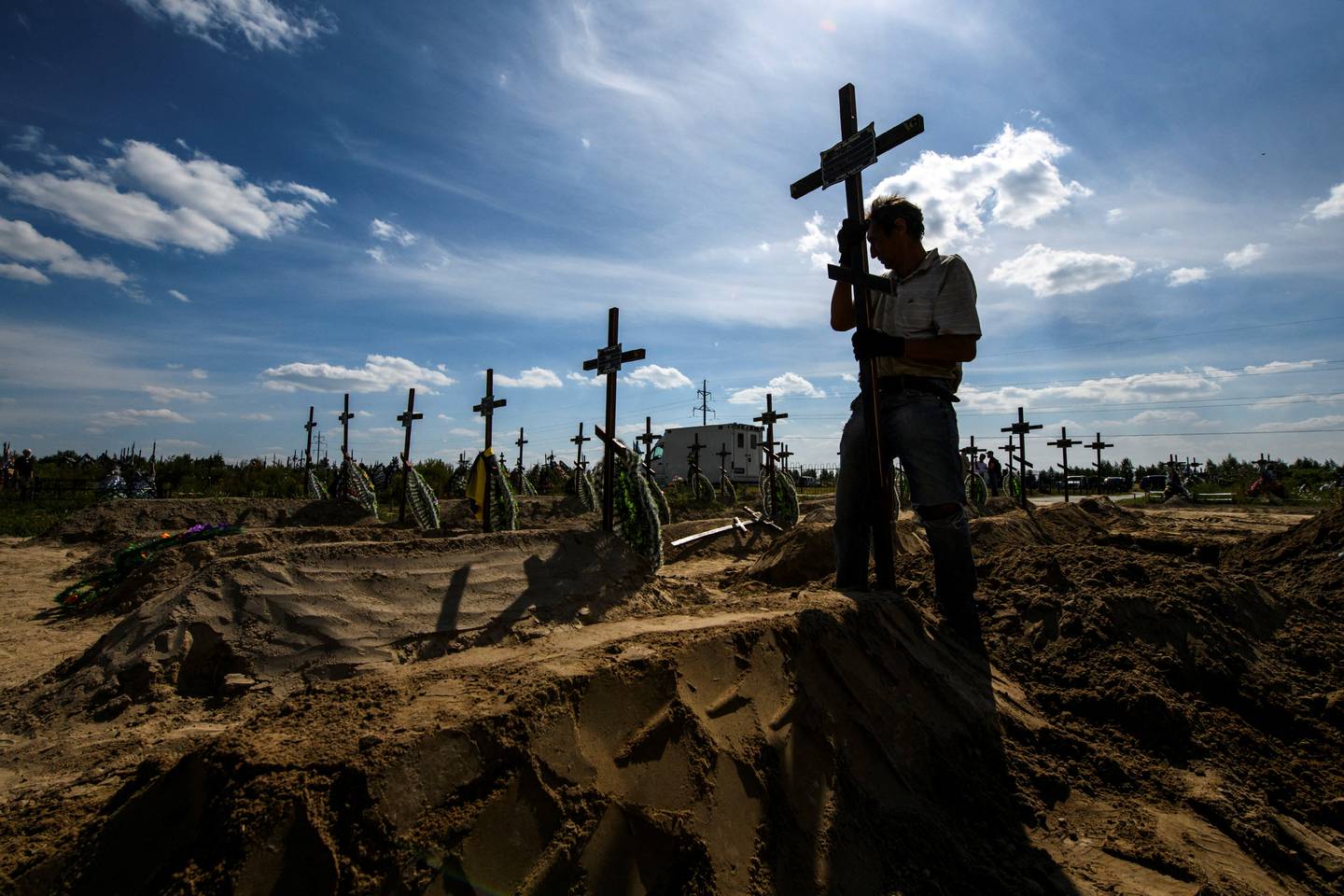 A volunteer places a cross on a grave of one of 15 unidentified people killed by Russian troops, during a ceremony in the town of Bucha. Reuters 
