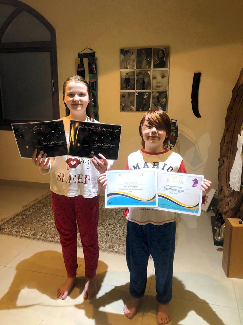 Sophie and Alex holding their artwork during home learning days.