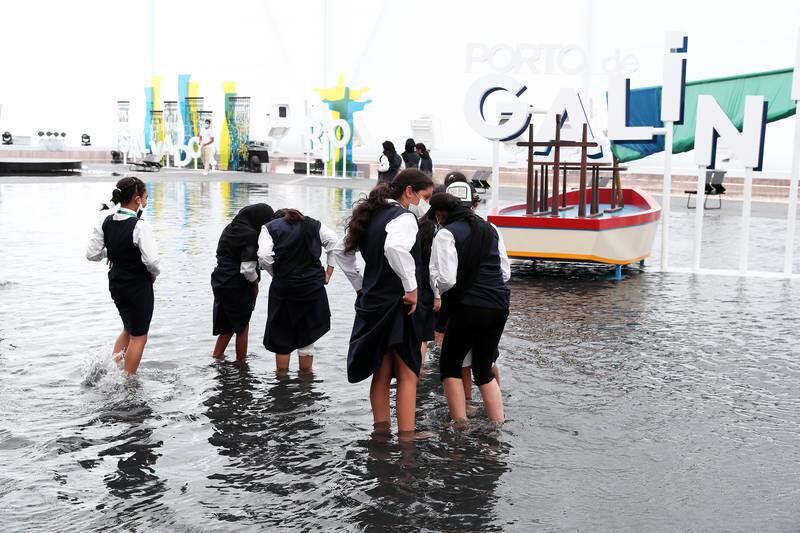 Visitors dip their feet in the water at the Brazil Pavilion.