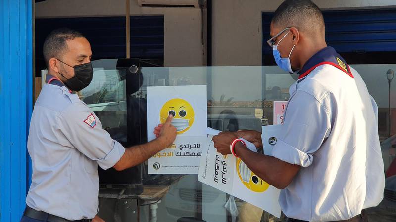 Libyan medical workers stick informative notices on a shop window during an awareness campaing on Covid-19 at the Friday market in the capital Tripoli. AFP