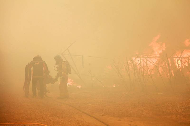 Firefighters walk through the smoke and haze from the  wildfire. AFP
